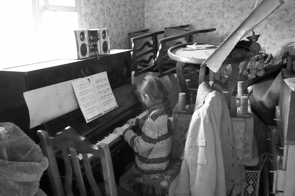 A small girl plays piano in a village bombed by the Russians